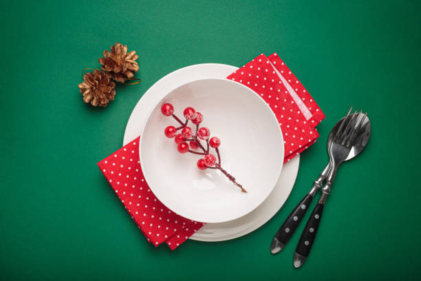 Christmas table setting decorated with fir branches and holly berries on green background