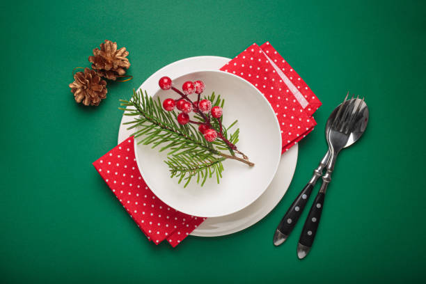 istock Christmas table setting decorated with fir branches and holly berries on green background 2185273576