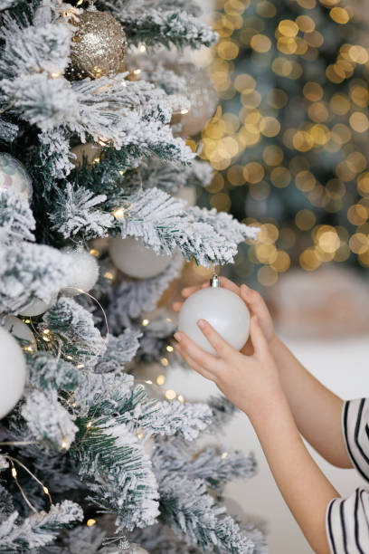 istock Children's hands hang a white ball on a Christmas tree. 2185273747
