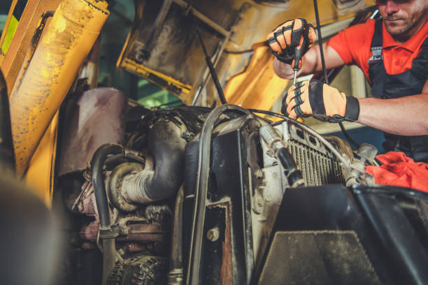 Mechanic Repairing Heavy Machinery Engine in Workshop During Daylight Hours