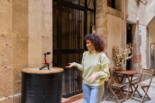 Young woman vlogger recording content for her online channel in a charming alleyway, using a microphone and enjoying the urban setting
