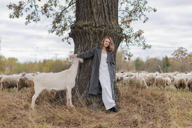 Blonde woman in coat in field with sheep