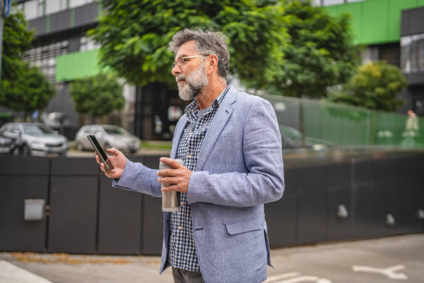 istock senior man drink coffee from thermos and use cellphone on break 2185279931