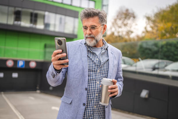 istock senior man drink coffee from thermos and use cellphone on break 2185280146