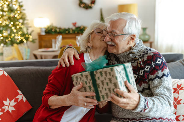 istock Happy senior couple sharing a joyful moment with Christmas gift exchange 2185284485
