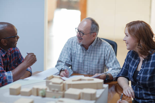 istock Senior man discusses architectural plans with Black ethnicity designer colleague teamwork group meeting in design urban planning office 2185285071