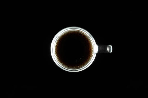 istock Black coffee in a illuminated cup surrounded by a black background. 2185286154