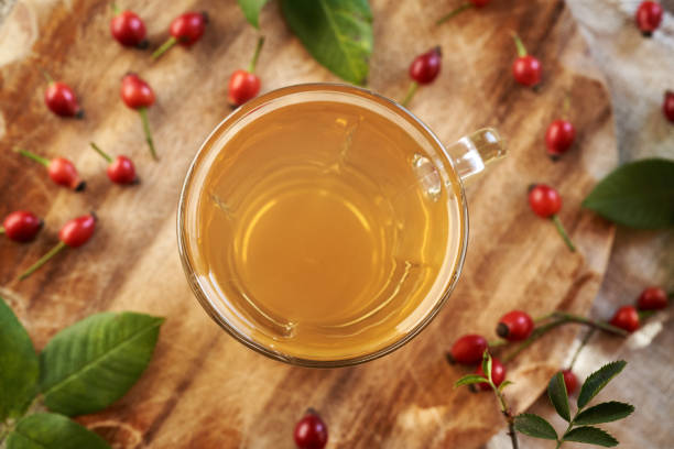 A cup of rose hip tea on a table with fresh berries, top view