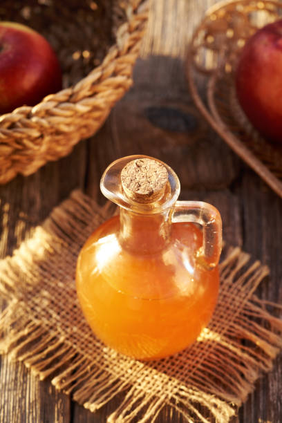 istock Unfiltered apple cider vinegar with red apples on a table in sunlight 2185287471