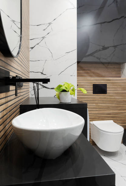 istock Interior decor. Ceramic bathroom sink with black water tap and brown striped tile on the wall and toilet with marbled effect on the wall. Real estate. Vertical. 2185290360