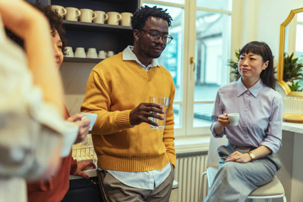 istock Diverse group of business people drinking coffee in the kitchen and discussing projects they are working on together 2185291213