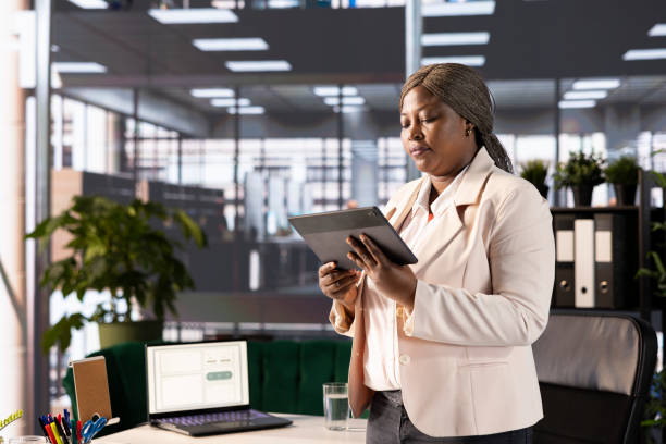 Businesswoman standing in office, using tablet