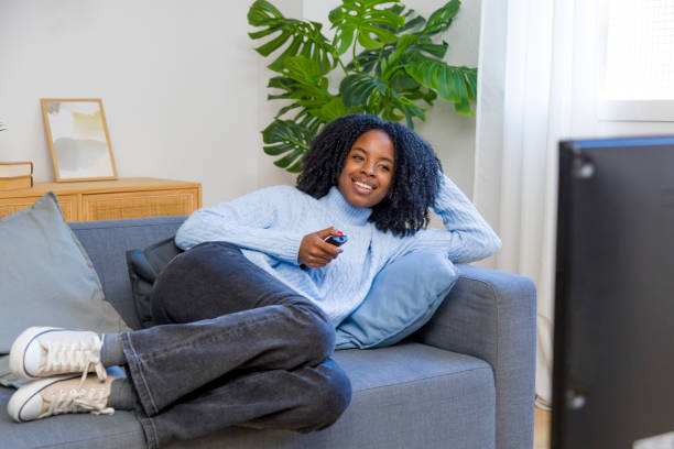 Young woman relaxing on sofa watching television at home
