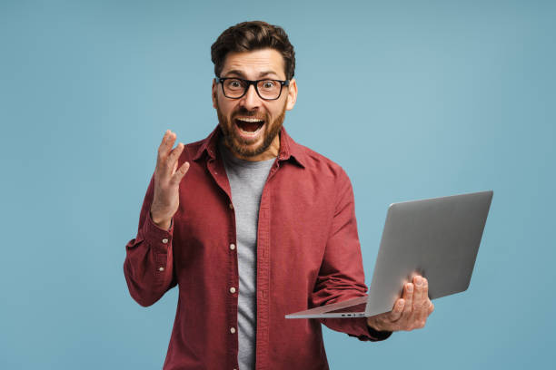 istock Excited, happy Hispanic man, it specialist, using laptop, screaming, isolated on blue background 2185299719