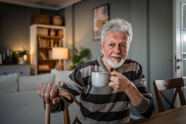 istock A look into the past. Grandfather drinking coffee, pensive with a walking cane 2185301676