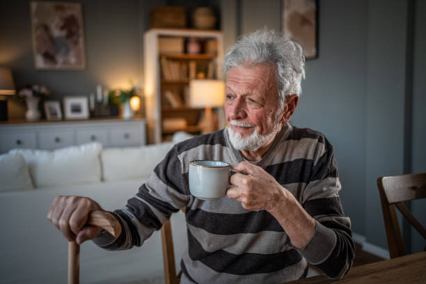 istock A look into the past. Grandfather drinking coffee, pensive with a walking cane 2185301691