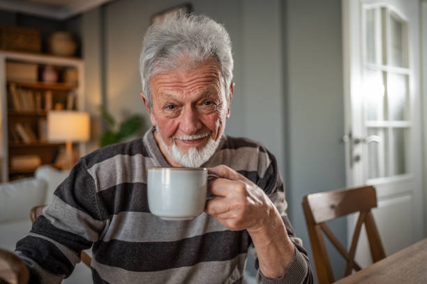 istock An elderly man drinking coffee, leaning on a walking cane 2185301738
