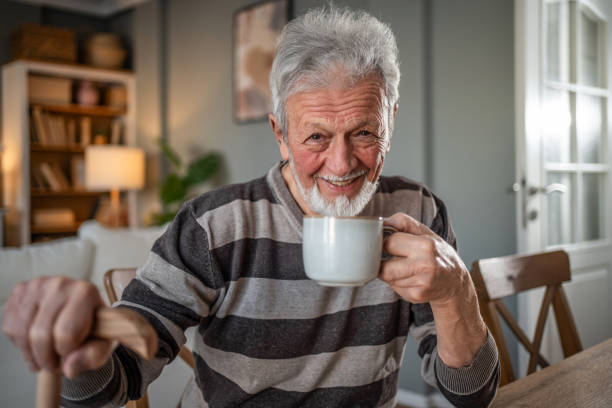 istock An elderly man drinking coffee, leaning on a walking cane 2185301742