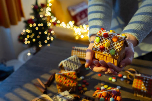 A woman is holding a DIY Gingerbread house at Christmas