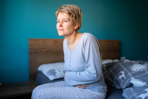 istock Middle-aged woman is sitting in her bed while having stomachache 2185303201