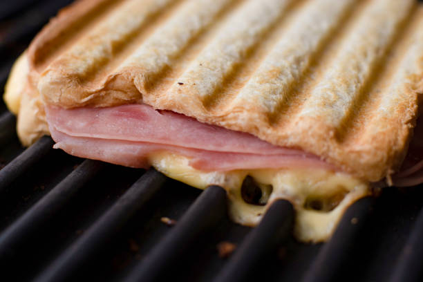 Photo of a delicious sandwich made with bread, cheese and ham on the grill, toasted bread and melting cheese, homemade food, fast food, tasty