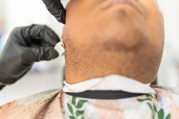 Close-up of a client neck while barber using razor to cut beard