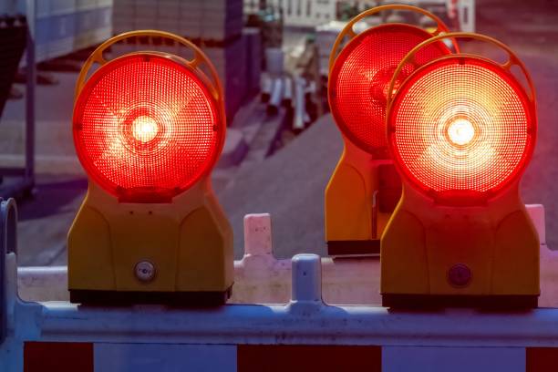 Red warning lights flashing on construction site barrier at dusk