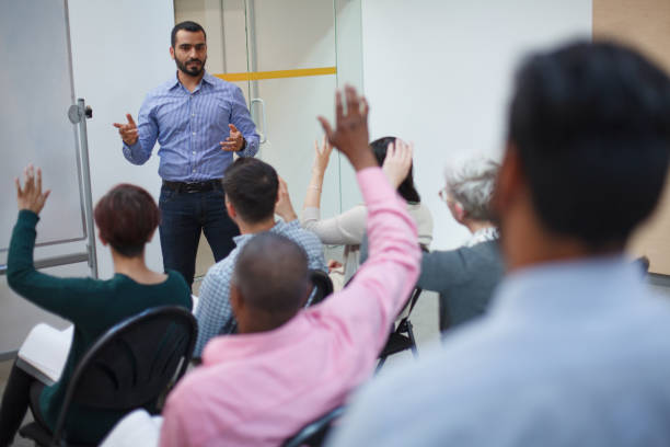 istock Middle Eastern mid adult man teacher talking teaching leading discussion with students hand raised in training seminar in school classroom for education training 2185316970