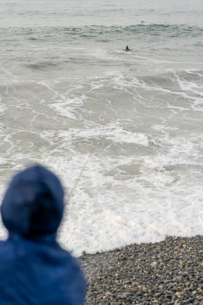 Vertical wide view photo with copy space of a latin young fisherman inside the water attached with rope to a bag on the beach