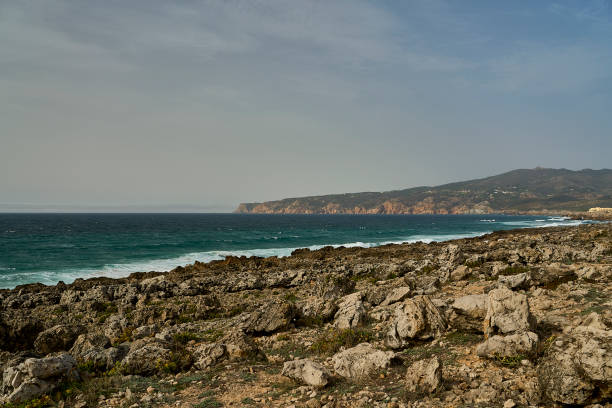 waves breaking at the rugged rocky coastline at cabo da roca, the western most point of european mainland, along the atlantic ocean of Portugal with steep cliffs and blue water.