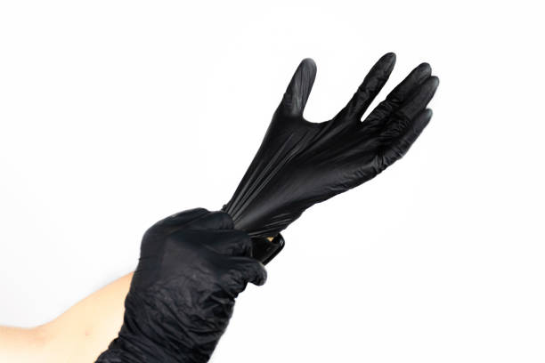 istock person putting on a black latex glove on white background. 2185323854