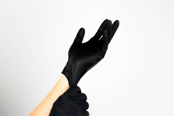 istock person putting on a black latex glove on white background. 2185323913