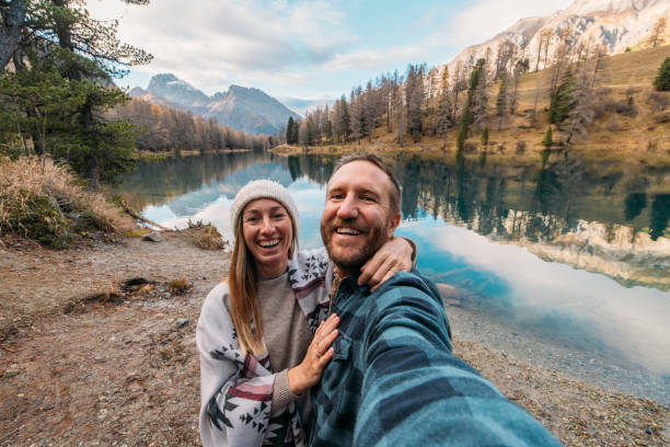 istock Smiling Couple Taking a Selfie by Mountain Lake 2185324331