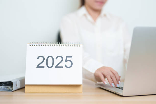 istock 2025 Year Calendar on table with business woman using laptop computer, working and writing in office. countdown, Happy New Year, Resolution, Year End and New Start and Goals Plan Action Concept 2185329484