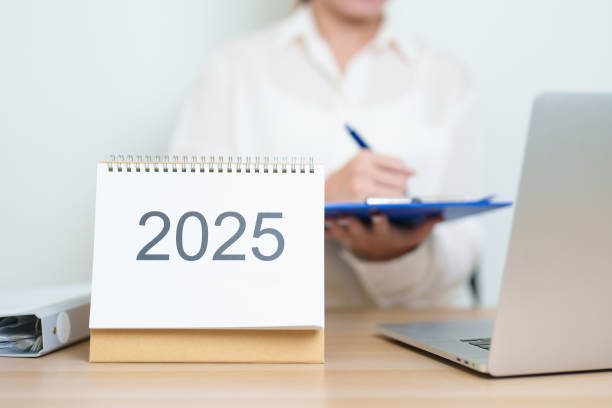 istock 2025 Year Calendar on table with business woman using laptop computer, working and writing in office. countdown, Happy New Year, Resolution, Year End and New Start and Goals Plan Action Concept 2185329560