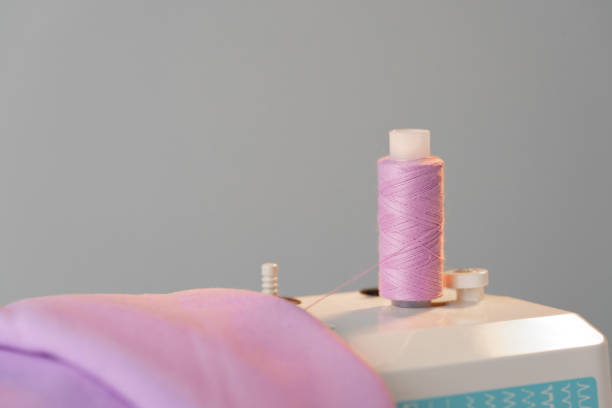 Close-up view of a sewing machine with a spool of pink thread placed on top