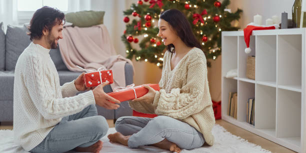 istock Joyful Couple Sharing Holiday Presents in Festive Home Setting 2185336963