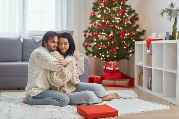 istock Loving Couple Embracing by Christmas Tree in Cozy Living Room 2185337607