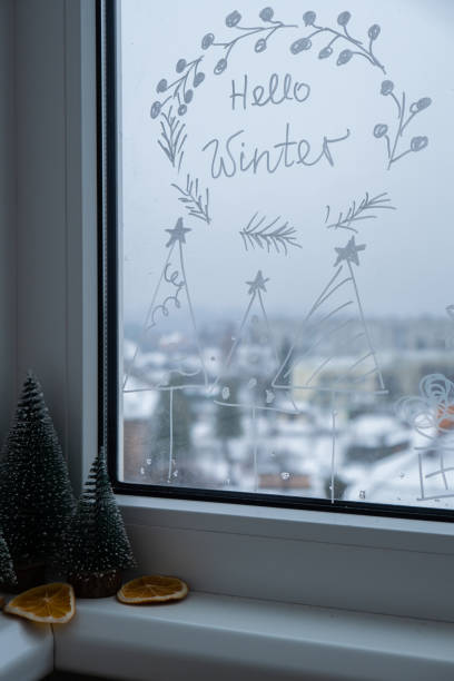 istock Painted window with white marker. Christmas tree decoration on big clear window. Snowy winter outside. Holiday 2185338117