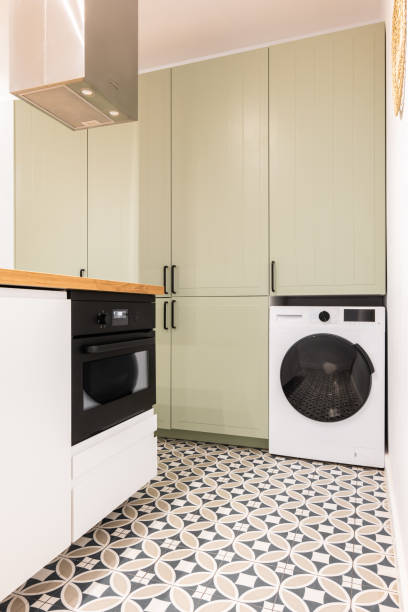 istock Part of spacious kitchen with modern appliances with black elements. Large built-in wooden cabinet for kitchenware and utensils in beige color with black handles. Floor is made of marble mosaic tiles. 2185342211