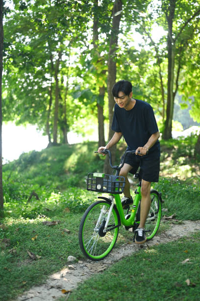 istock Young attractive man riding a bike through the forest road 2185343984