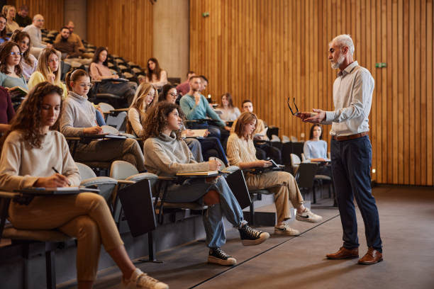 istock Mature professor talking to his student on a class at lecture hall. 2185346002