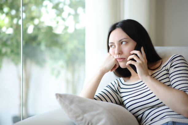 Bored asian woman waiting in a phone conversation at home stock photo