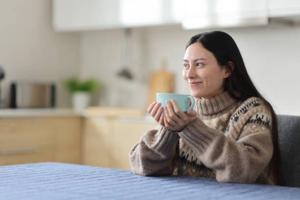 istock Asian woman relaxing in the kitchen in winter drinking tea 2185348747