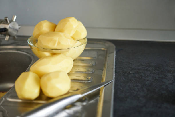 istock Peeled potatoes. Peel the potatoes in the kitchen sink. 2185349061