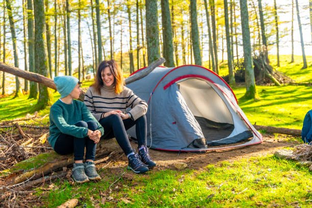 istock Mother and boy sitting next to camping tent 2185349837