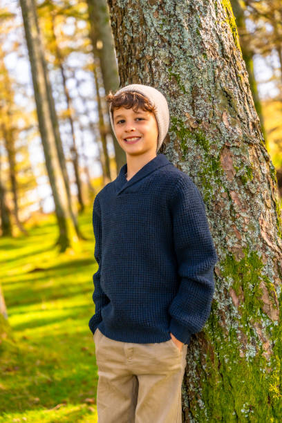 istock Teenage model with urban clothes leaning on tree trunk 2185351415