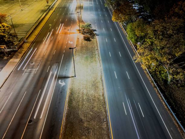 istock City highway at night with light trails and autumn trees. 2185354674