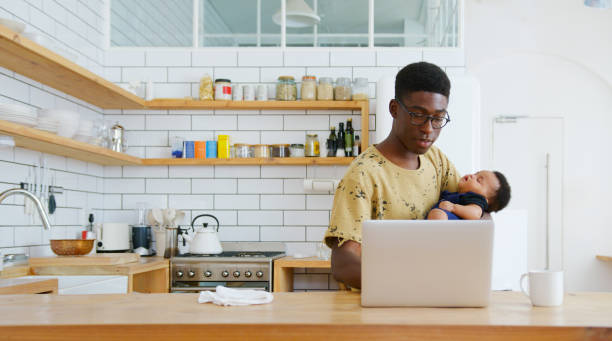 istock Multi-Tasking Father Holds Sleeping Baby Son Whilst Working On Laptop In Kitchen 2185355304