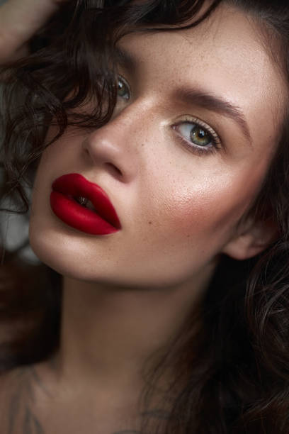 istock Woman with captivating green eyes and defined cheekbones, emphasizing her bold red lipstick and intricate makeup. Soft curls frame her face beautifully 2185355428